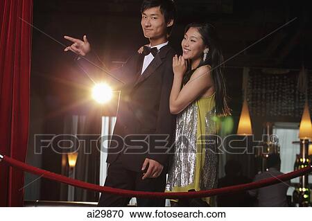 Stock Image - Young couple standing behind red rope at night. Fotosearch