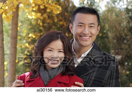 Young couple standing together under the trees View Large Photo Image Stock Photograph - Young couple standing together under the trees. Fotosearch