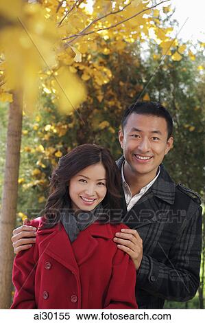 Young couple standing together under the trees View Large Photo Image Stock Photography - Young couple standing together under the trees. Fotosearch