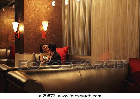 Stock Image - Young couple talking to each other in a club at night. Fotosearch