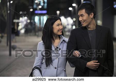 Young couple wearing coats walking on the street at night View Large Photo Image Stock Photography - Young couple wearing coats walking on the street at night. Fotosearch