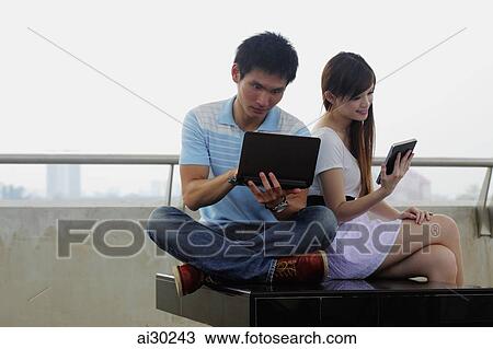 Young couple working on laptop and tablet computers outdoors View Large Photo Image Stock Image - Young couple working on laptop and tablet computers outdoors. Fotosearch