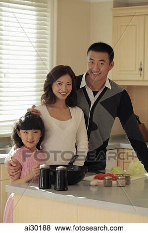 Young family cooking together in kitchen View Large Photo Image Stock Photo - Young family cooking together in kitchen. Fotosearch