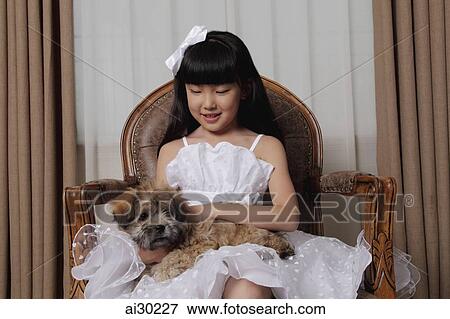 Young girl dressed up in white dress holding a puppy View Large Photo Image Stock Photo - Young girl dressed up in white dress holding a puppy. Fotosearch