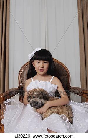 Stock Photograph - Young girl dressed up in white dress holding a puppy. Fotosearch