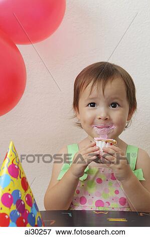 Young girl eating a cupcake at a birthday party View Large Photo Image Stock Photo - Young girl eating a cupcake at a birthday party. Fotosearch