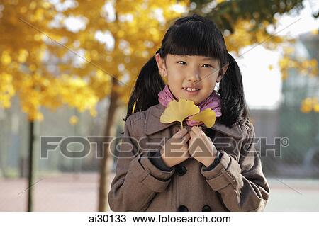 Young girl holding Autumn leaves outdoors View Large Photo Image Stock Image - Young girl holding Autumn leaves outdoors. Fotosearch