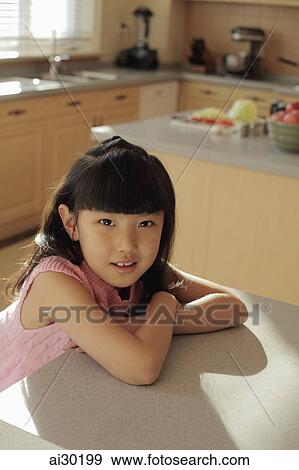 Young girl sitting at the kitchen counter View Large Photo Image Stock Photo - Young girl sitting at the kitchen counter. Fotosearch