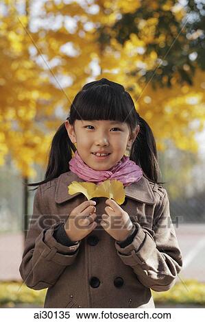 Young girl smiling and holding Autumn leaves outdoors View Large Photo Image Stock Photography - Young girl smiling and holding Autumn leaves outdoors. Fotosearch