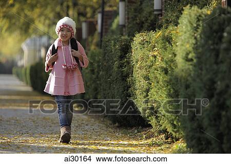 Young girl walking down street wearing pink coat and hat and backpack View Large Photo Image Picture - Young girl walking down street wearing pink coat and hat and backpack. Fotosearch