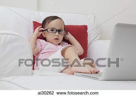 Young girl wearing glasses and playing with a laptop computer View Large Photo Image Stock Image - Young girl wearing glasses and playing with a laptop computer. Fotosearch
