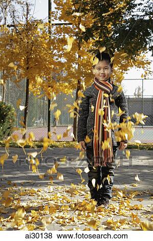 Stock Photo - Young leaves falling on young boy. Fotosearch