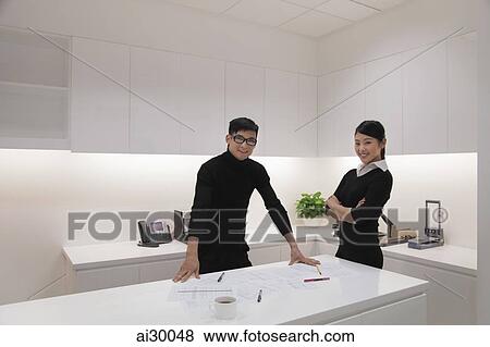 Young man and woman standing in modern office View Large Photo Image Stock Photo - Young man and woman standing in modern office. Fotosearch