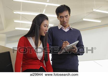Young man and woman working together in an office View Large Photo Image Picture - Young man and woman working together in an office. Fotosearch