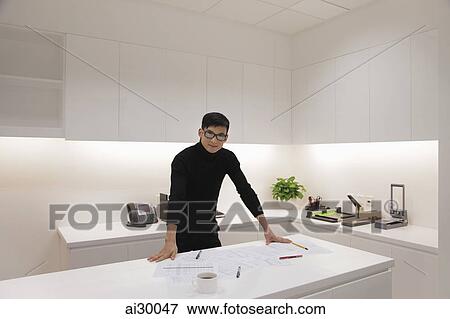 Young man dressed in black standing in modern office View Large Photo Image Stock Photo - Young man dressed in black standing in modern office. Fotosearch