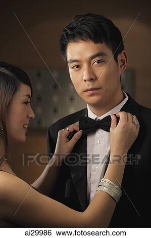 Stock Photograph - Young man getting his bow tie straightened by a woman. Fotosearch