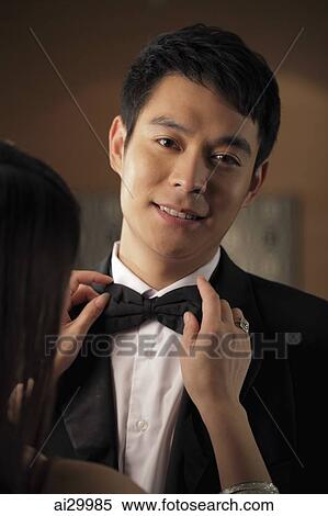 Young man getting his bow tie straightened by a woman View Large Photo Image Stock Photography - Young man getting his bow tie straightened by a woman. Fotosearch