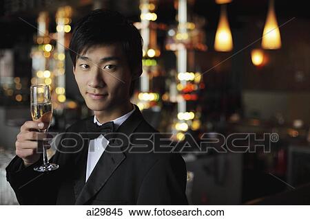 Young man in a tuxedo holding a glass of champagne View Large Photo Image Stock Photography - Young man in a tuxedo holding a glass of champagne. Fotosearch