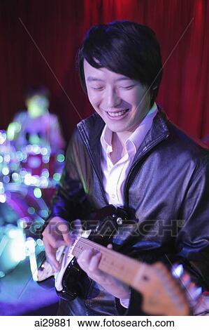 Young man playing guitar in a club View Large Photo Image Stock Image - Young man playing guitar in a club. Fotosearch