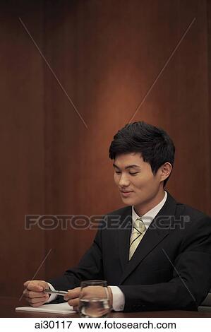 Young man sitting at desk View Large Photo Image Stock Photo - Young man sitting at desk. Fotosearch