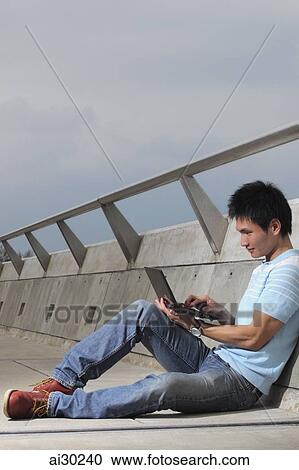 Young man sitting on floor using laptop View Large Photo Image Stock Image - Young man sitting on floor using laptop. Fotosearch