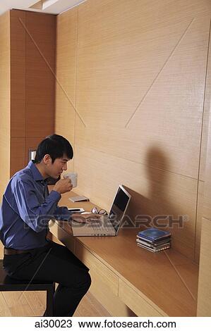 Young man working on laptop computer drinking coffee View Large Photo Image Stock Image - Young man working on laptop computer drinking coffee. Fotosearch