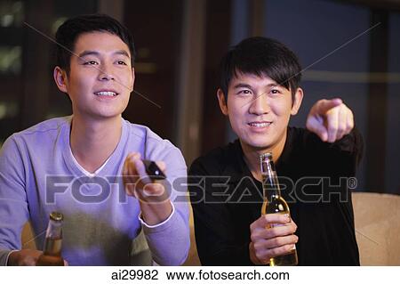 Young men watching TV together and holding bottles of beer View Large Photo Image Stock Image - Young men watching TV together and holding bottles of beer. Fotosearch