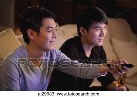 Young men watching TV together and smiling View Large Photo Image Stock Image - Young men watching TV together and smiling. Fotosearch