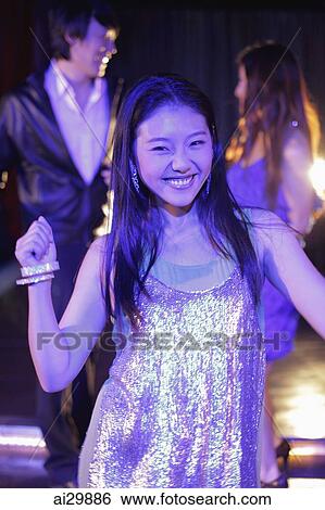 Young woman dancing at night with people in background View Large Photo Image Stock Photograph - Young woman dancing at night with people in background. Fotosearch