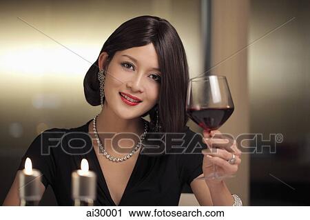 Stock Image - Young woman drinking wine during a candle lit dinner. Fotosearch