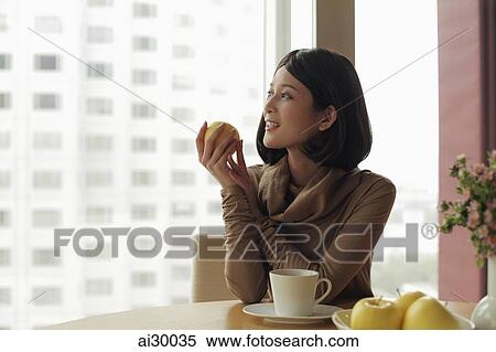 Young woman holding apple and looking out window View Large Photo Image Stock Photography - Young woman holding apple and looking out window. Fotosearch