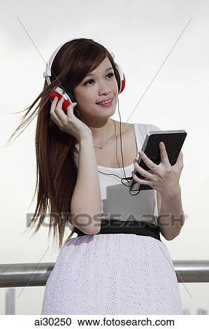 Young woman listening to music on a tablet computer View Large Photo Image Stock Image - Young woman listening to music on a tablet computer. Fotosearch