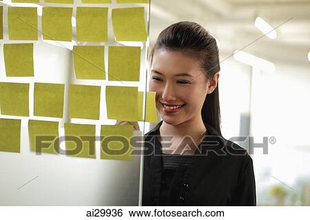 Young woman looking at stick on notes View Large Photo Image Stock Photograph - Young woman looking at stick on notes. Fotosearch