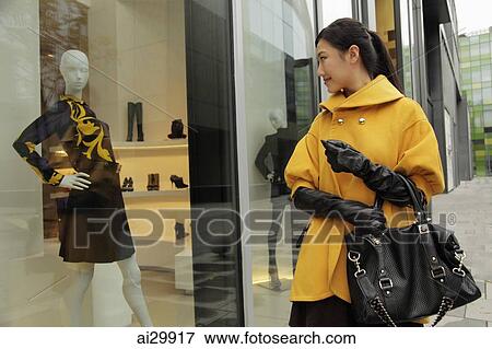 Stock Photo - Young woman looking in shop window. Fotosearch