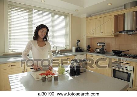Young woman preparing food in her kitchen View Large Photo Image Stock Image - Young woman preparing food in her kitchen. Fotosearch