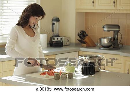 Stock Photography - Young woman preparing food in her kitchen. Fotosearch
