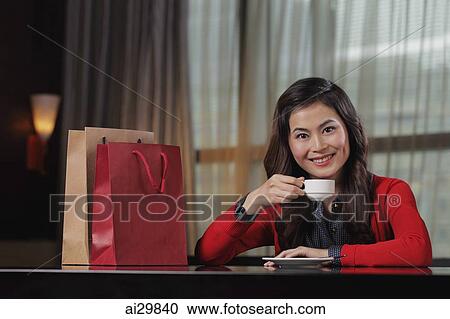 Young woman sitting in restaurant with shopping bags holding cup View Large Photo Image Stock Image - Young woman sitting in restaurant with shopping bags holding cup. Fotosearch