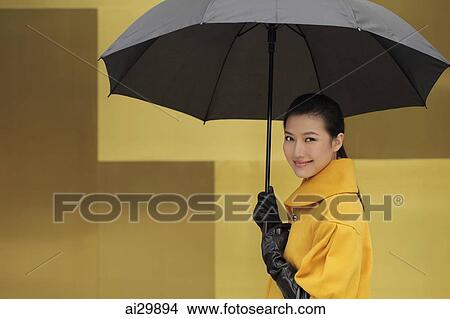 Picture - Young woman smiling at camera holding an umbrella. Fotosearch