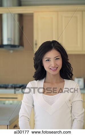 Stock Photo - Young woman smiling in her kitchen. Fotosearch