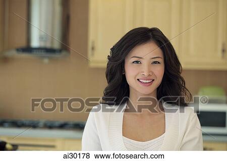 Stock Photo - Young woman smiling in her kitchen. Fotosearch