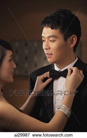 Young woman straightening a young man's bow tie View Large Photo Image Stock Photo - Young woman straightening a young man's bow tie. Fotosearch