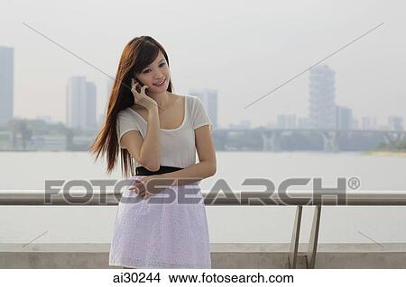 Picture - Young woman talking on phone outdoors. Fotosearch