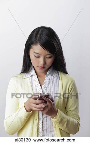 Stock Image - Young woman texting on her phone. Fotosearch