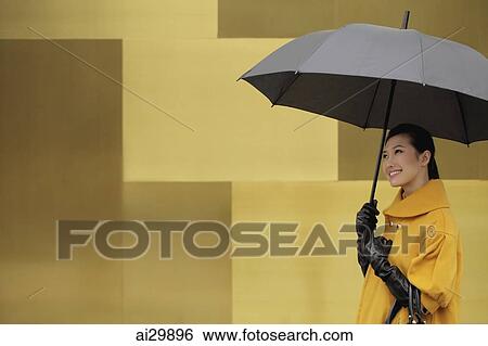 Young woman wearing a coat and gloves holding an umbrella View Large Photo Image Stock Photograph - Young woman wearing a coat and gloves holding an umbrella. Fotosearch