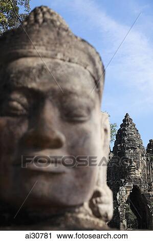 Stock Image - Close up of stone carving with Bayon Temple in background, Angkor Wat, Cambodia. Fotosearch