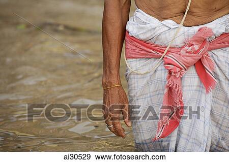 Stock Photo - Crop shot of a man standing in shallow waters of the Ganges River, Varanasi, India. Fotosearch