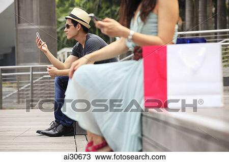 Cropped shot of people sitting outdoors looking at phones View Large Photo Image Stock Image - Cropped shot of people sitting outdoors looking at phones. Fotosearch