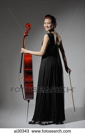 Elegantly dressed woman holding a cello and smiling View Large Photo Image Stock Image - Elegantly dressed woman holding a cello and smiling. Fotosearch