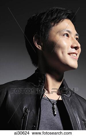 Picture - Head shot of profile of young man smiling in leather jacket.. Fotosearch