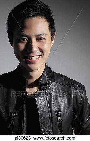 Stock Image - Head shot of young man smiling in leather jacket. Fotosearch